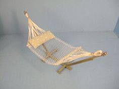 a small white hammock sitting on top of a wooden stand next to a blue wall