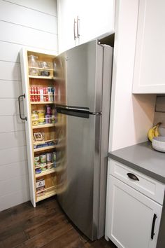 a stainless steel refrigerator freezer sitting inside of a kitchen next to white cupboards