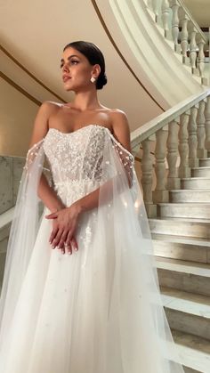 a woman in a wedding dress standing on the stairs with her hand on her hip