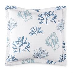 a blue and white pillow with seaweed print on the front, sitting on a white surface