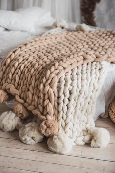 a large woven blanket sitting on top of a wooden floor next to pillows and blankets