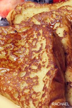 some french toast with syrup and fruit on the side is sitting on a yellow plate