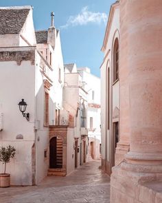 an alley way with white buildings and potted plants