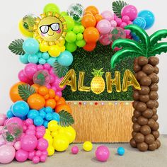 there are balloons and pineapples in front of the sign that says aloha