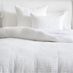 a bed with white sheets and pillows on it