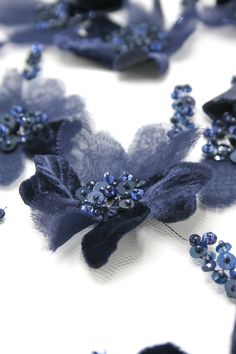 several blue flowers on a white surface with sequins and beads in the center