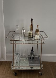 a bar cart filled with liquor bottles and glasses on top of a hard wood floor