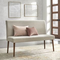 a white couch sitting on top of a rug next to a wooden frame window sill