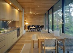 an open kitchen and dining area with wood flooring, large windows, and wooden furniture