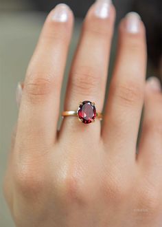 a woman's hand with a ring on it and a red stone in the middle