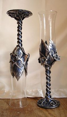 two metal vases sitting on top of a wooden table