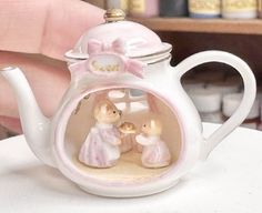 a miniature teapot with two figurines in it
