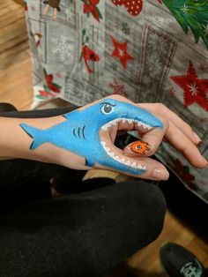 someone has painted a shark on their hand with an orange fish in it's mouth