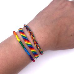 a person's arm with three different colored bracelets on it and one is holding the other