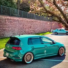 a green car parked in a parking lot next to a brick wall