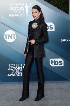 a woman in black pants and jacket at an awards event with her hand on her hip