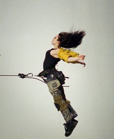 a woman flying through the air on top of a parachute with her hair blowing in the wind