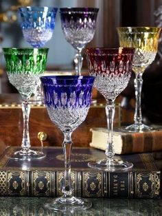 four wine goblets sitting on top of a table next to an old book