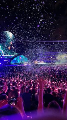 a large crowd at a concert with confetti in the air