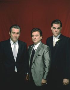 three men in suits and ties posing for a photo with a red backdrop behind them