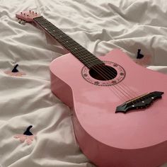 a pink guitar laying on top of a bed