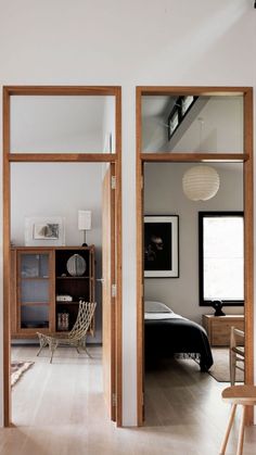 an open door leading to a bedroom with white walls and wood trimming on the floor