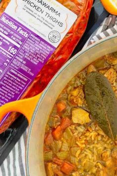 a large pot filled with food next to a bag of chicken thighs and an orange slice