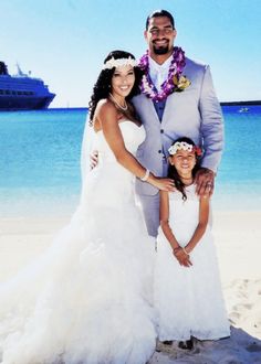 a man and woman standing on top of a sandy beach next to the ocean with a cruise ship in the background