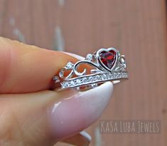 Crown Garnet red Heart Cubic Zirconia SOLID sterling stamped 925 silver Tarnish free sizes 5-11 Some sizes are sold out. But will be replenished shortly Top of ring is 8.3mm. Band width is 2.3 and shank is 2mm The Red CZ center stone is .3ct 4.5mm Round stone Number of clear CZ's are 16 This is set in a Bezel setting Nothing but the best from my custom jewelry store. Email me if you have any questions. Red Heart Ring, Promise Ring Silver, Quinceanera Jewelry, Crown Engagement Ring, Crown Ring Princess, Ring Luxury, Heart Engagement Rings, Engagement Rings For Women, Colored Engagement Rings