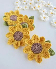 three crocheted sunflowers sitting next to each other on a white surface