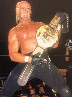 a man holding a wrestling belt in front of a crowd