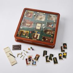 a wooden box with several pieces of board games in it and some cards on the table