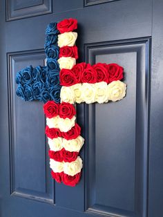 a cross made out of red, white and blue flowers hangs on the front door