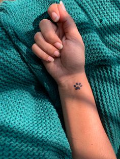 a person holding their hand with a small dog paw tattoo on it's wrist