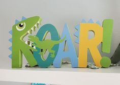 two wooden letters that spell out the word roar with a dinosaur figure next to them