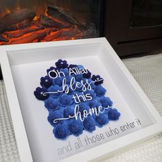 a white frame with blue flowers in front of a fire place that reads, or all that bliss this home and all those who enter it