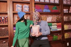 a man and woman standing next to each other in front of a store filled with candy