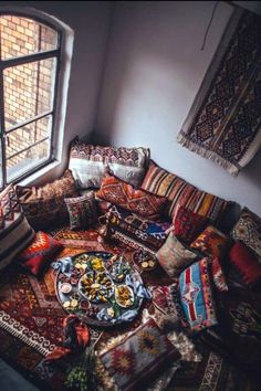 a living room filled with lots of pillows and rugs next to a large window