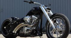 a black and silver motorcycle parked in front of a metal building on a sunny day