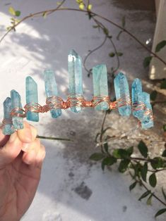 a person holding up some kind of wire with blue crystals on it's end