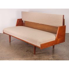 a wooden bench with beige upholstered fabric on the back and armrests