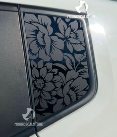 the side window of a white car with flowers on it's decal sticker
