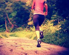 a woman running down a dirt road in the woods