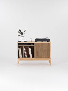 a record player sitting on top of a wooden cabinet next to a potted plant