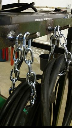 a bunch of black hoses and chains hanging from the side of a metal rack