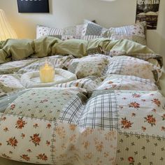 a candle is lit on a bed with floral comforter and pillow cases in a bedroom