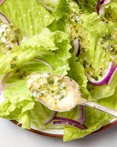 a plate with lettuce, onions and cheese on it next to a fork