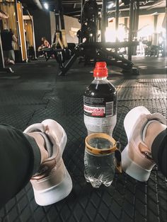 someone's feet and water bottle sitting on the ground in front of a gym