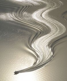 the sun shines through some wavy lines in the sand on the beach at low tide