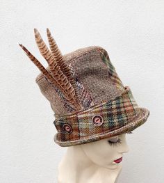 This unusual tall top hat has an 8 section crown made from various recycled tweed and wool fabrics making it a sustainable fashion choice. The removable band with button detailing has brown velvet on one side and tweed on the other for an alternate look. The feather brooch is also removable. * Size M/L to fit headsize 58cms/22.83inches * Crown height 19cms/7.48inches * Dryclean only To see more of my hats please click https://www.etsy.com/uk/shop/OverToYou I design, pattern cut and create all my Patchwork, Sewing Hats, Feather Brooch, Tweed Top, Crown Heights, Wool Top, Top Hats, Brown Velvet, I Design